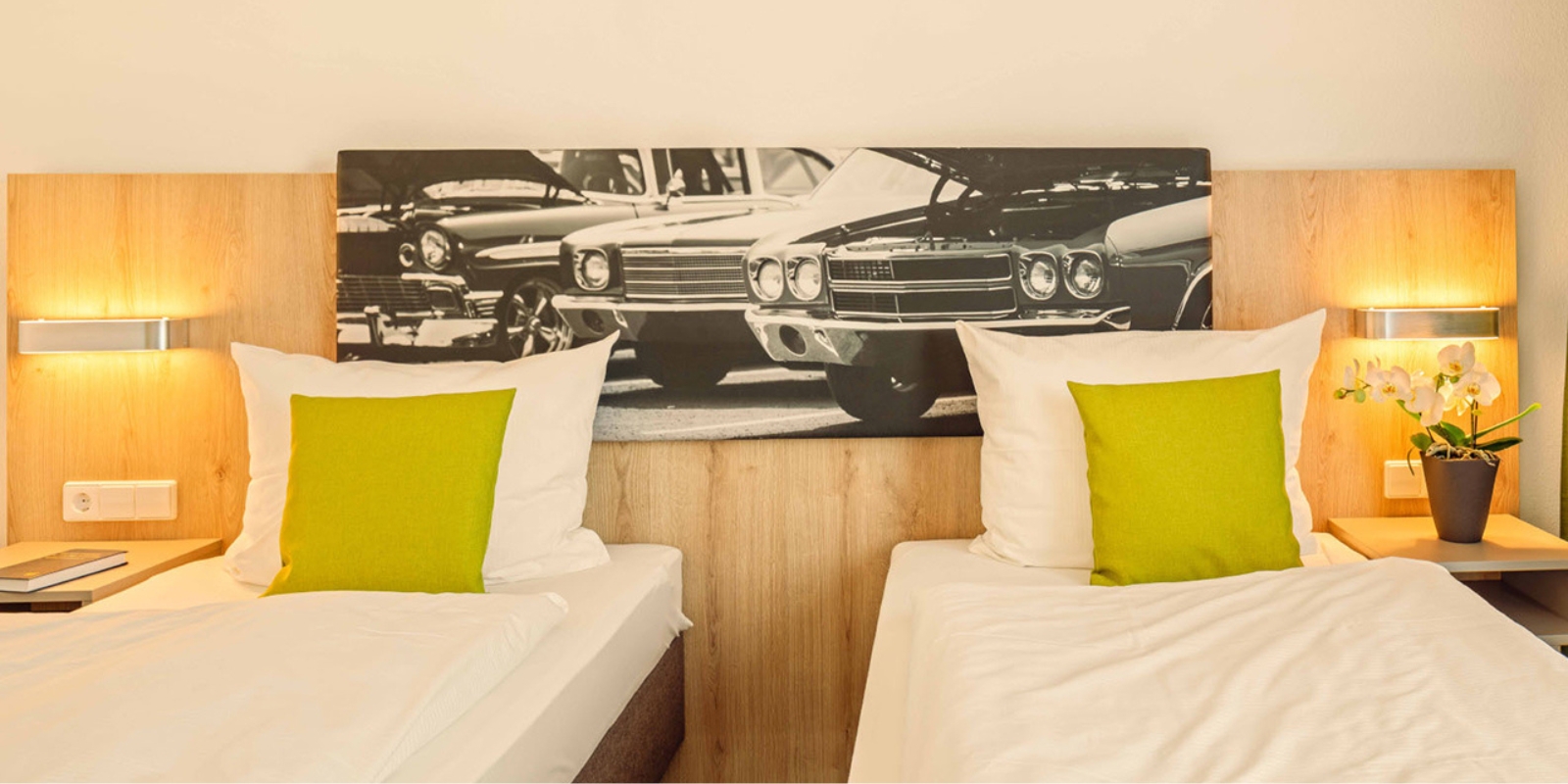 Doppelzimmer im Highway Hotel Herbolzheim mit zwei Betten und Oldtimer-Bild über dem Kopfteil