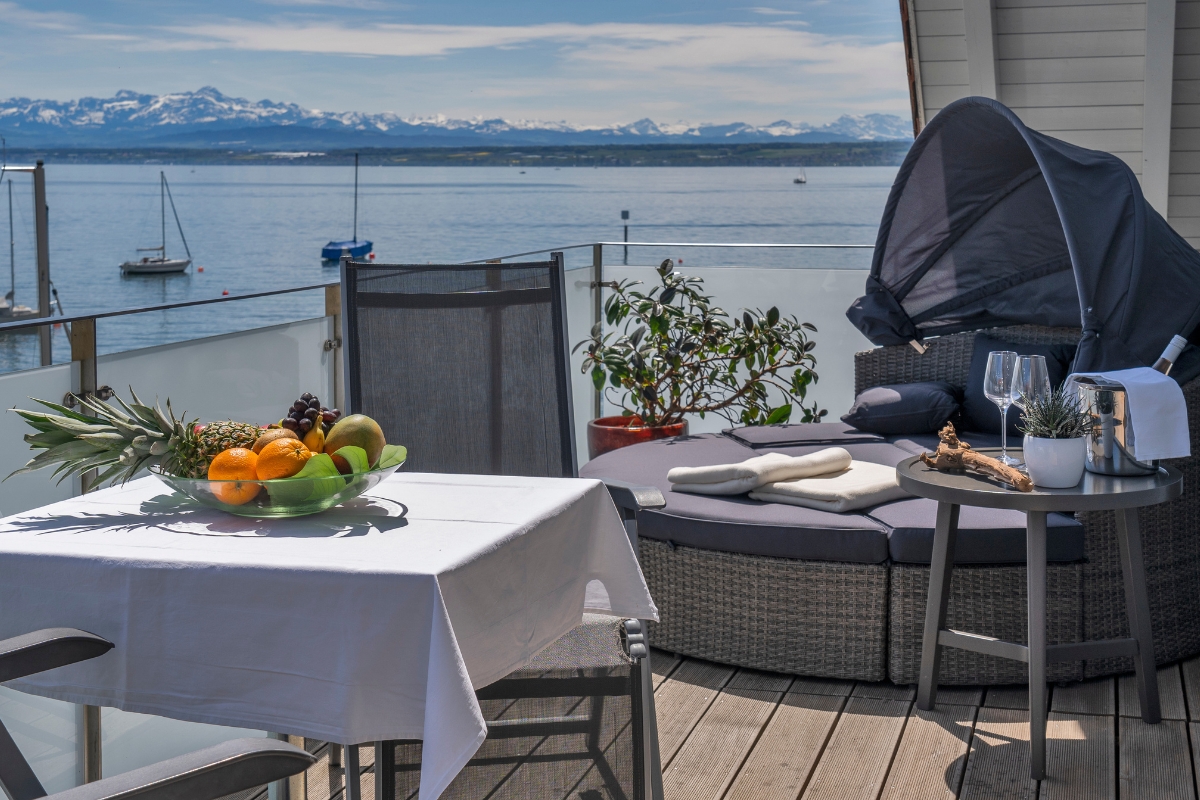 Balkon mit Loungebett und Blick über den Bodensee auf die Alpen