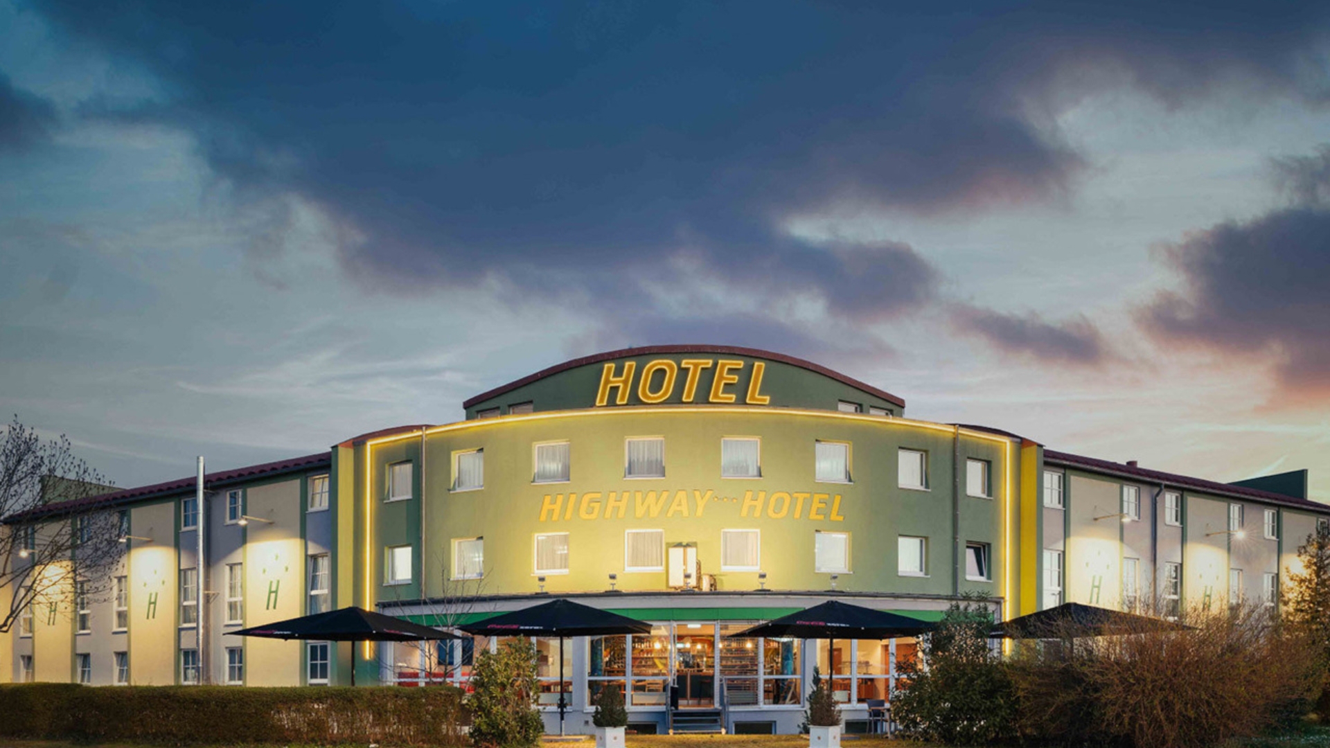 Beleuchtete Vorderansicht des Highway Hotel in Herbolzheim in der Abenddämmerung