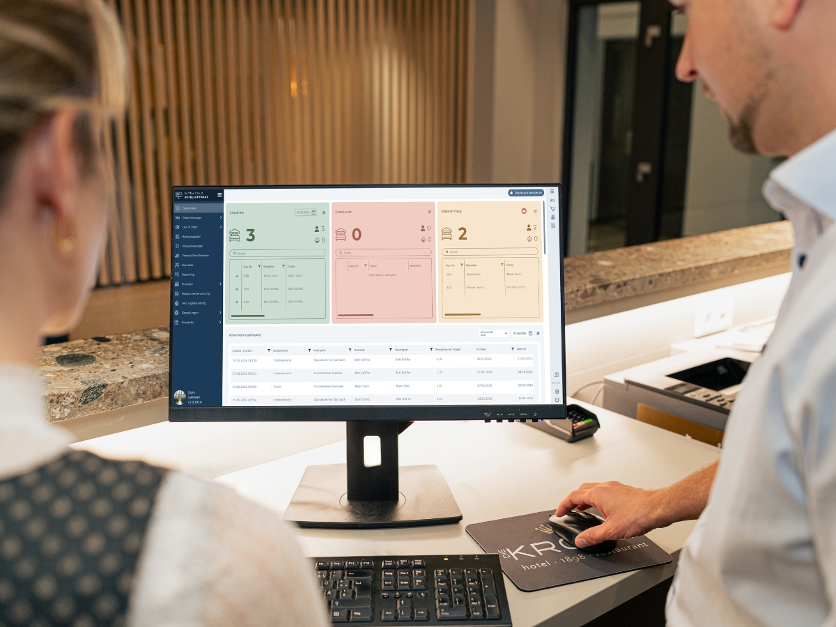 Zwei Mitarbeitende an der Rezeption blicken auf das Dashboard der SoftTec Cloud Hotelsoftware
