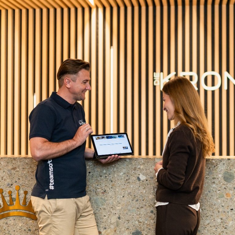 SoftTec Mitarbeiter zeigt einer Hotelière die Cloud Hotelsoftware auf dem Tablet an der Rezeption