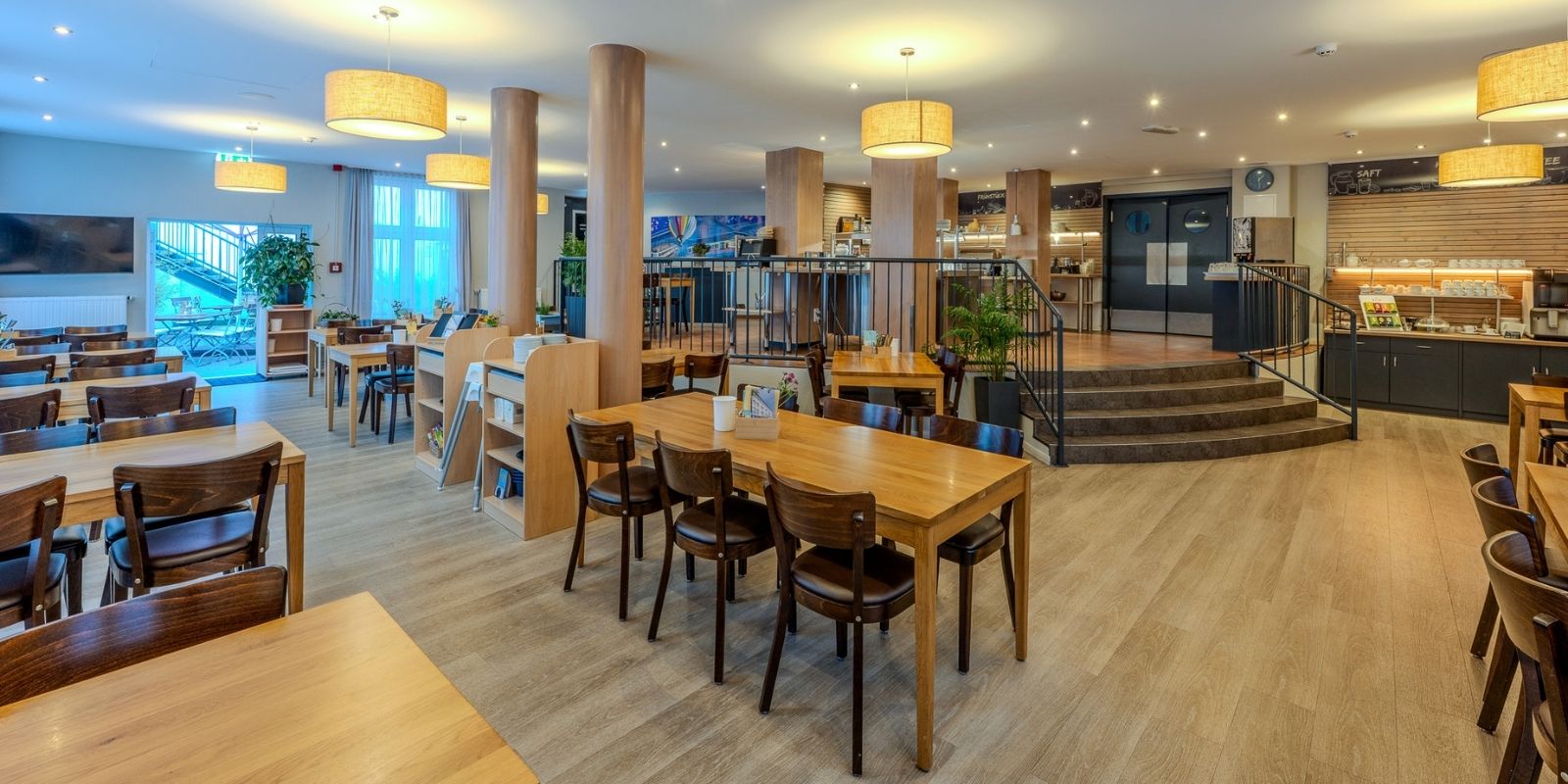 Frühstücksraum im Businesshotel Berlin mit Holztischen, Buffetbereich und Blick in den Innenhof