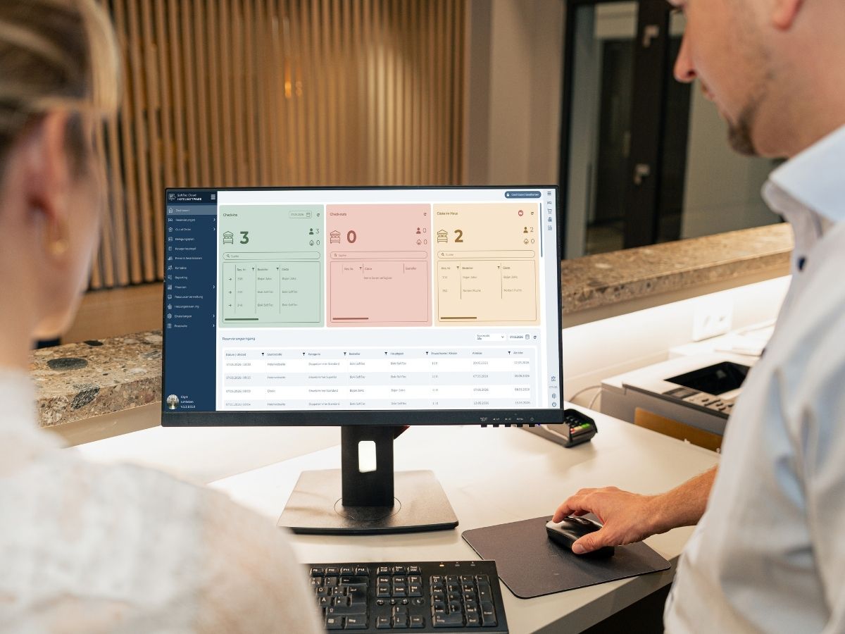 Zwei Mitarbeitende am Empfang des Businesshotel Berlin am Dashboard der SoftTec Cloud Hotelsoftware mit Check-ins, Check-outs und Reservierungseingang